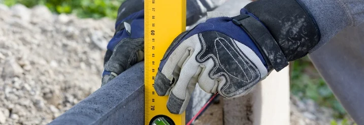 Person misst Holzbalken mit Wasserwaage aus